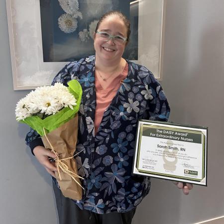 Nurse, Sarah Smith, holding a bouquet of flowers and an award certificate