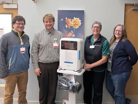 four care team member standing in a hospital hallway with a new, portable, disinfection device
