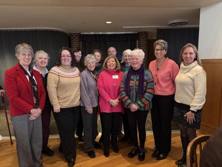 A group of smiling, older adults standing together in a lobby space. They are members of the hospital's auxiliary.