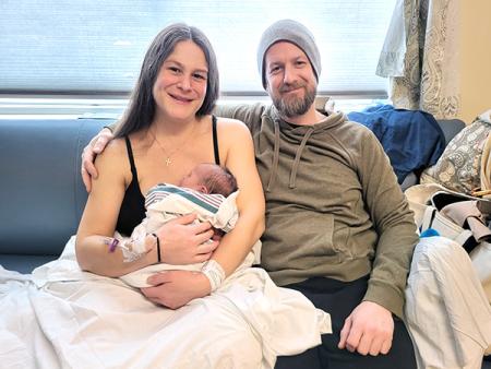 Two parents holding a newborn in a hospital room