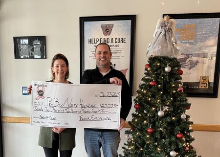 A man and a woman standing together holding an over-sized check for a donation presentation