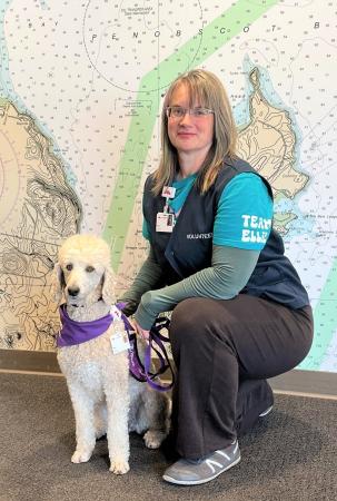 Ellie, a white poodle, sitting next to her owner, Anna Phillips