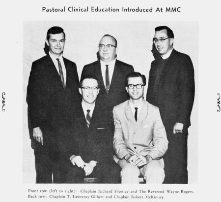 Five men sitting and standing together posing for a formal picture. The image is a copy of an old black and white photo.