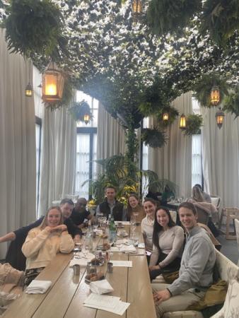 a group of adults sitting around a large dining table in a restaurant celebrating graduating from their residency