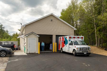Exterior of the MaineHealth IFT building - a two-bay, creme-colored garage with an ambulance parked outside