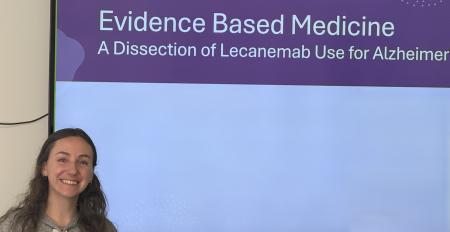 a woman standing next to a presentation screen on evidence based medicine