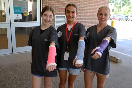 three students hold out their arms covered in casts as part of a casting exercise