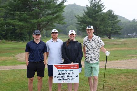 four adults, members of team drive brand studio, posing together on the greens during the Memorial Hospital golf tournament
