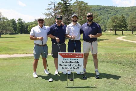 four adults, members of team heb engineers, posing together on the greens during the Memorial Hospital golf tournament