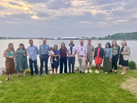 a group of adults standing together next to a large body of water