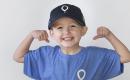 Young boy smiling and holding his arms up like a body-builder