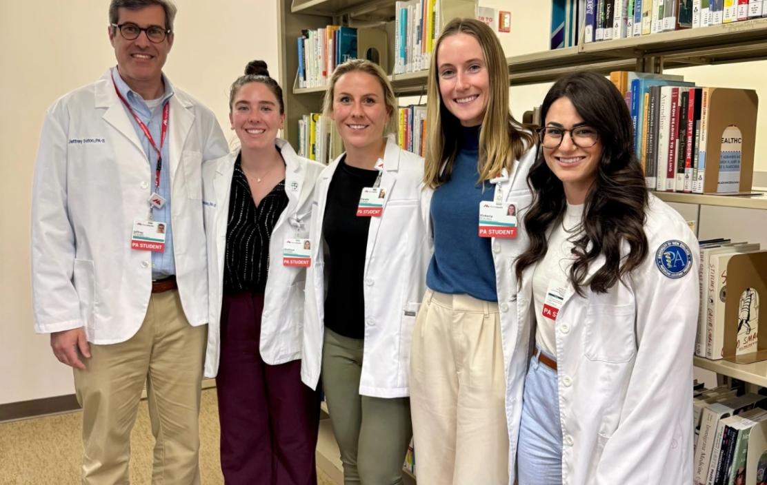 Five MaineHealth APP students stand together in a library