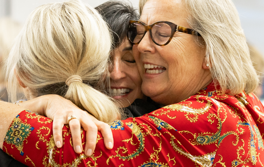 Three women hug at a MaineHealth Behavioral Health fundraising event