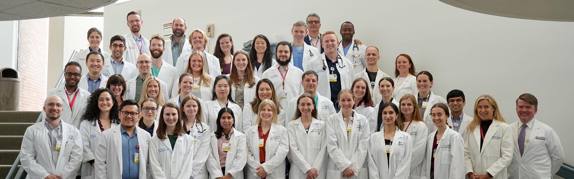 group photo of the internal medicine residents wearing their white lab coats and standing together on the stairs of the Dana Center