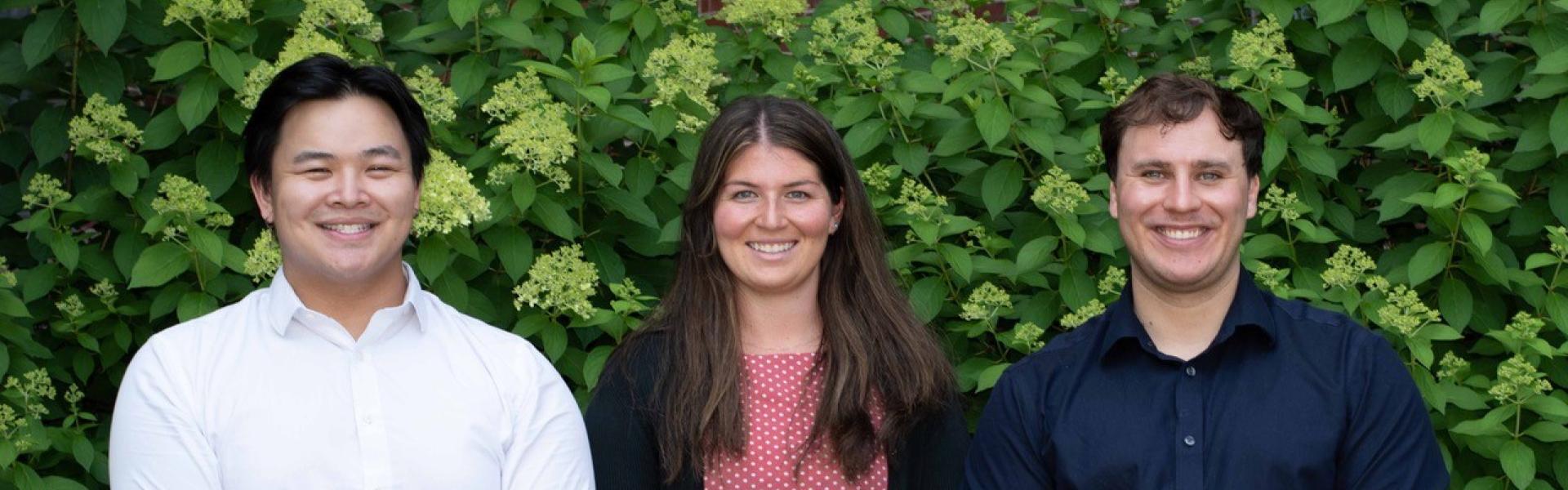 three pharmacy residents standing together outside in front of a green hedge