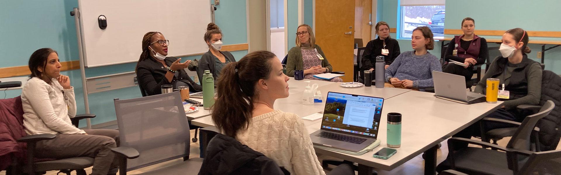 addiction medicine fellows sit around a table talking