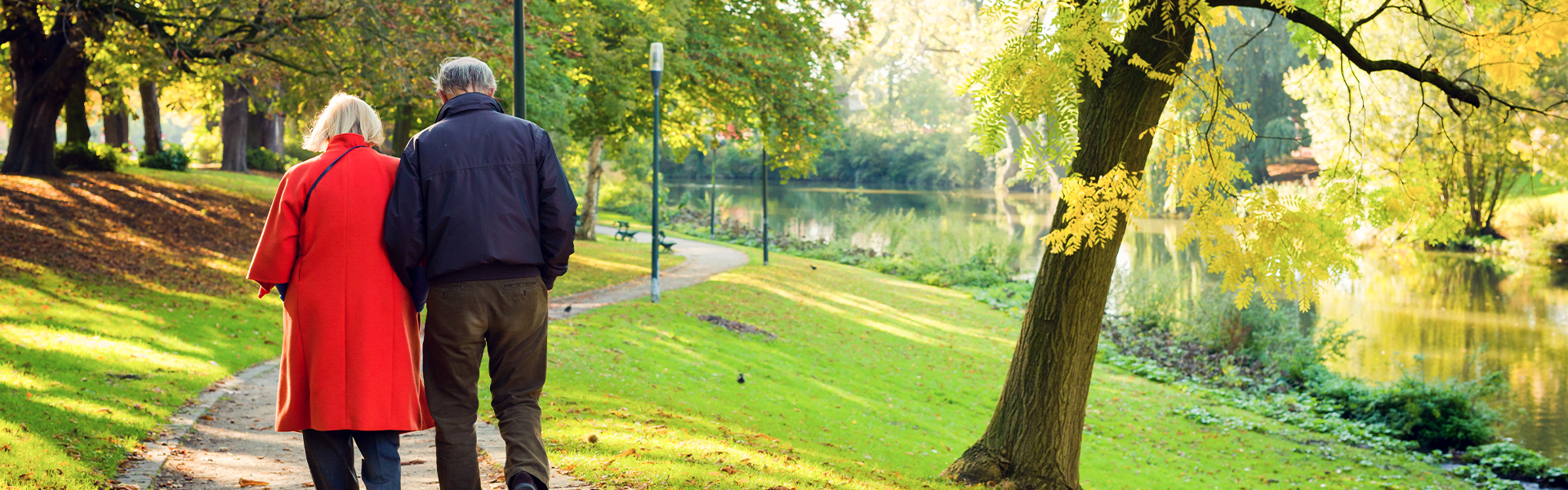 An older couple walking together on a path through a park on a bright day