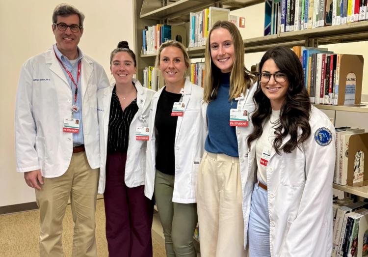 Five MaineHealth APP students stand together in a library
