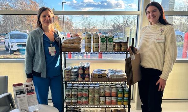 Katie Holm and Abigail Lacasse stand by a MaineHealth Help Yourself Shelf filled with free food