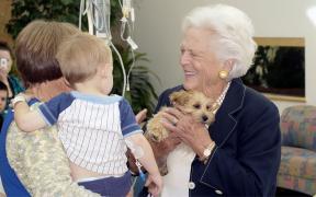 Former first lady Barbara Bush holds a puppy while speaking with patients and families