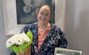 Nurse, Sarah Smith, holding a bouquet of flowers and an award certificate