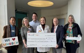 a group of adults presenting an oversized check to the MHBBCH