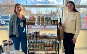 Katie Holm and Abigail Lacasse stand by a MaineHealth Help Yourself Shelf filled with free food