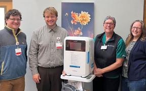 Four care team members stand with new disinfection equipment.