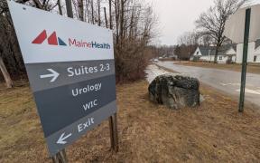 A large sign next to the road providing directions to MaineHealth Urology and WIC