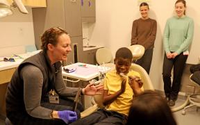 A young boy receives a dental exam in a dentist office while two care team members observe