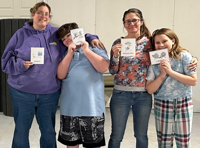 Two parents and two children stand together in a field house smiling and holding cards