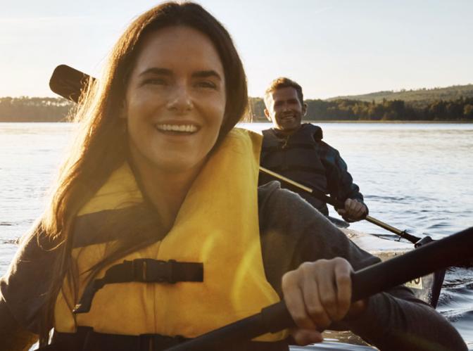 Two kayakers on a lake with bright sunshine in the background