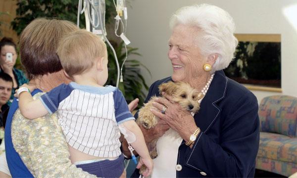 Former first lady Barbara Bush holds a puppy while speaking with patients and families