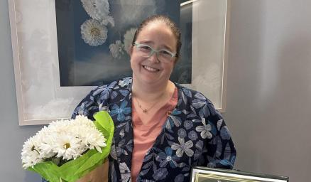 Nurse, Sarah Smith, holding a bouquet of flowers and an award certificate