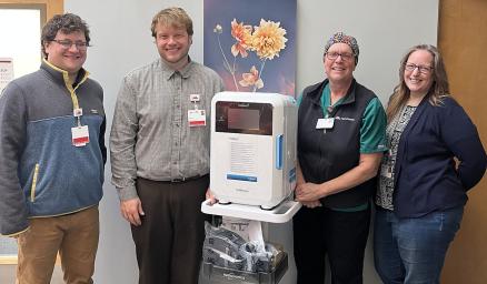 four care team member standing in a hospital hallway with a new, portable, disinfection device