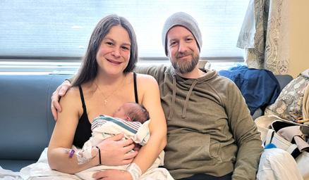 Two parents holding a newborn in a hospital room