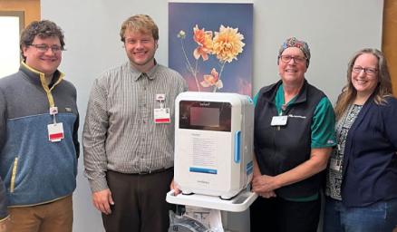 Four care team members stand with new disinfection equipment.