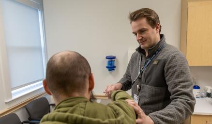 A MaineHealth care team member examines a patient's arm in an exam room