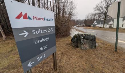 A large sign next to the road providing directions to MaineHealth Urology and WIC