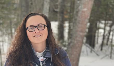 Megan Harvey standing outside in the snow in front of the woods