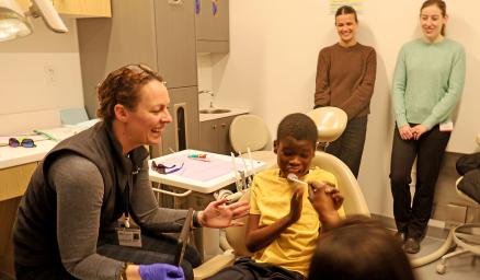 A young boy receives a dental exam in a dentist office while two care team members observe