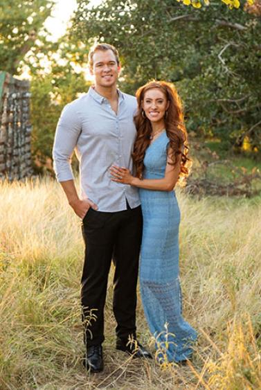 smiling young man and woman standing together in a pastoral country field